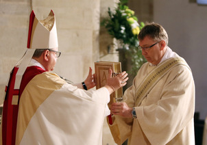 Bischof übergibt neuem Diakon das Evangelium. 