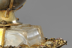 Kunst in Kürze: Das Kompositreliquiar: Unter dem mit einem Becher aus Wolkenachat bekrönten Bergkristall verbirgt sich ein silbervergoldetes Vögelchen, dessen Symbolik Rätsel aufgibt