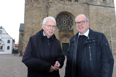 Veränderungen im Domkapitel zu Osnabrück: Zwei dunkel gekleidete Männer stehen vor einer Kirche.  
